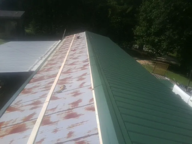 Old rusted panels beside newly installed green metal roofing — Wind Damage Roof Repair by Roofing Brothers in Pleasant Grove